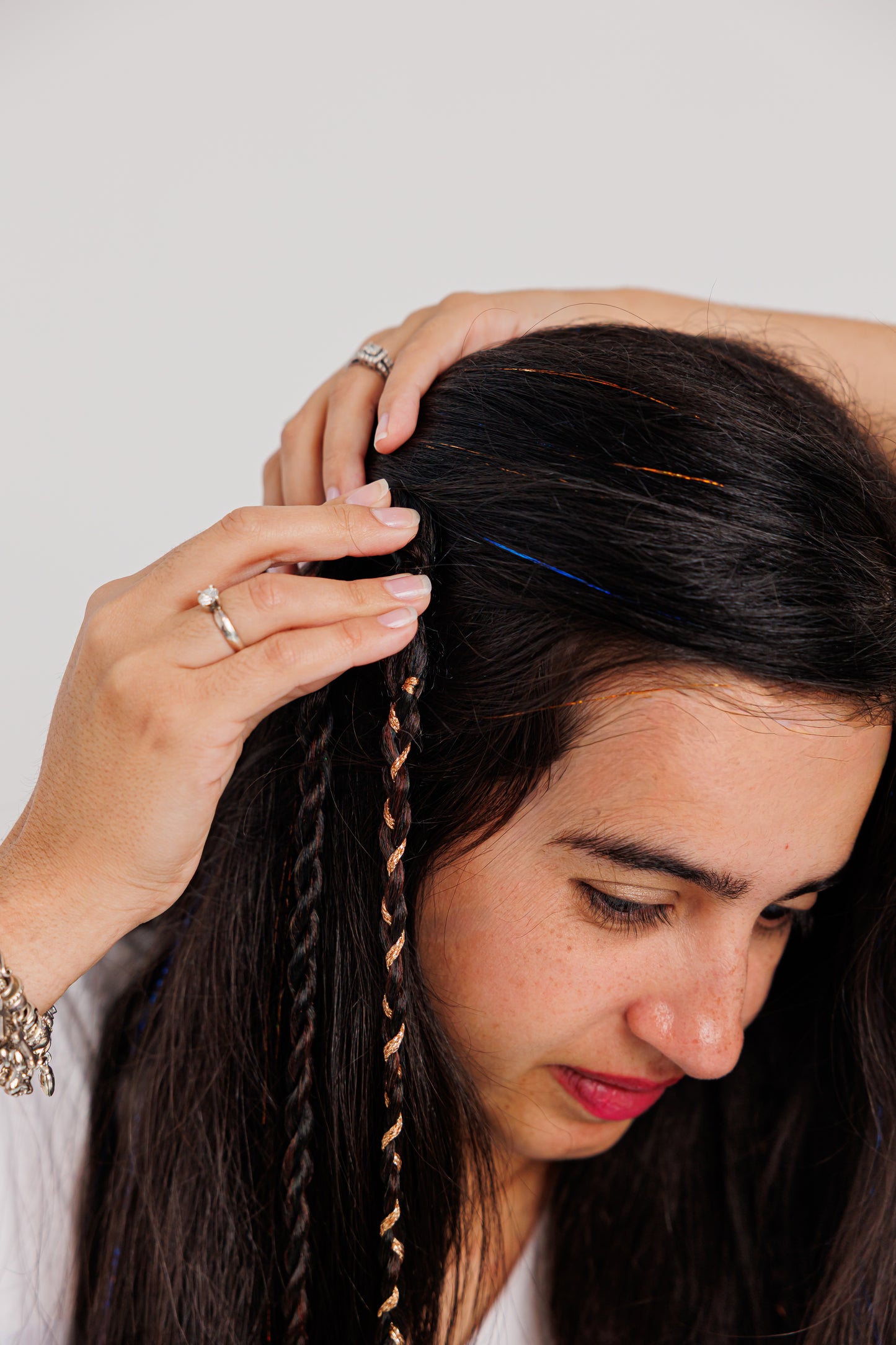 Woman clipping the braided hair against a plain background