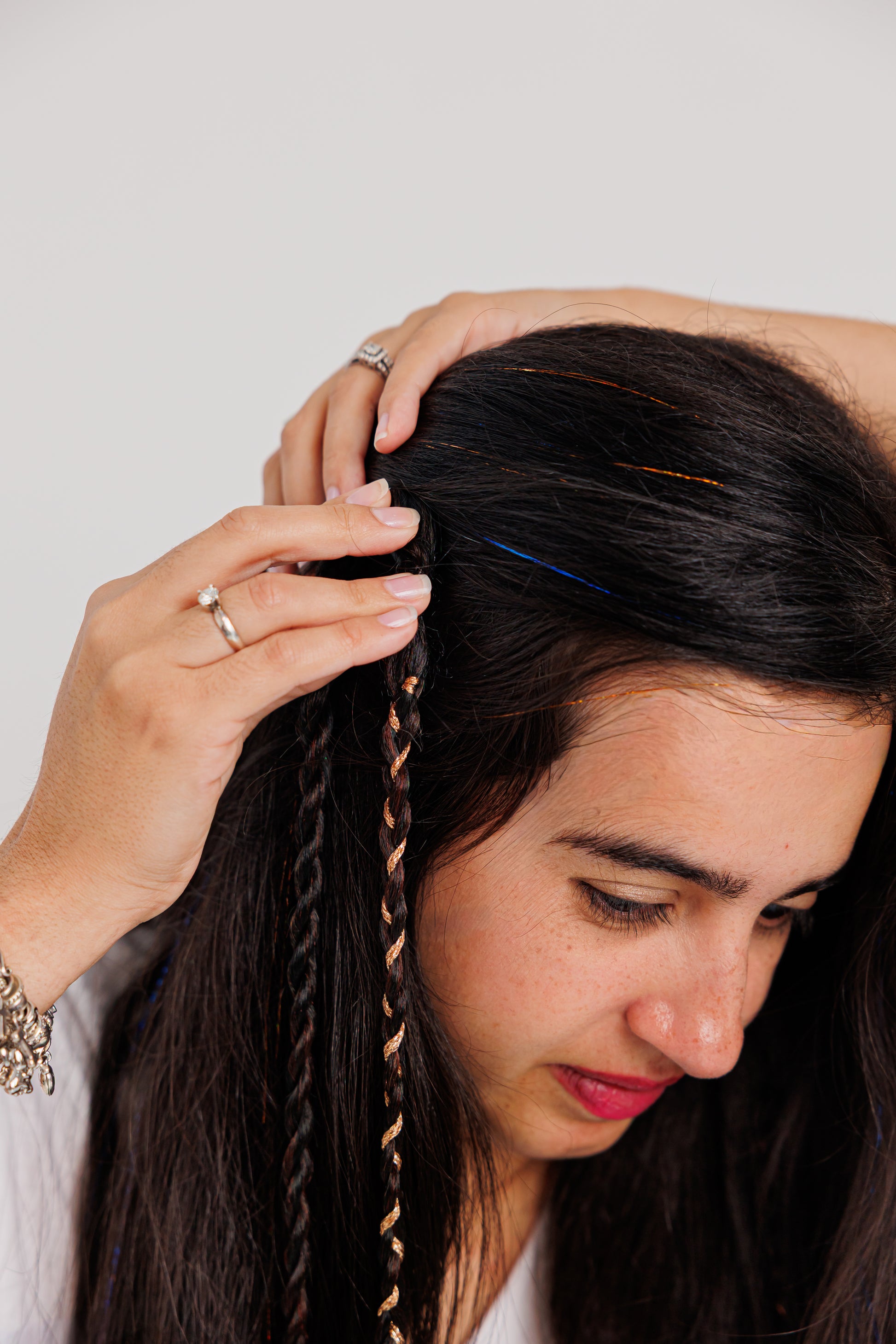 Woman clipping the braided hair against a plain background