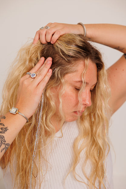 Woman with blonde hair getting her silver hair  clip ins styled against a plain background