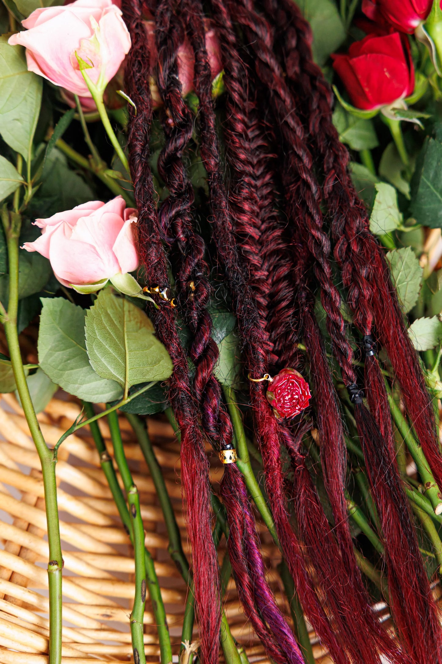 Magenta braided hair with beads and rose accessory over basket of pink and red roses.