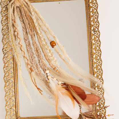 Decorative boho hair with feathers in front of a gold-framed mirror