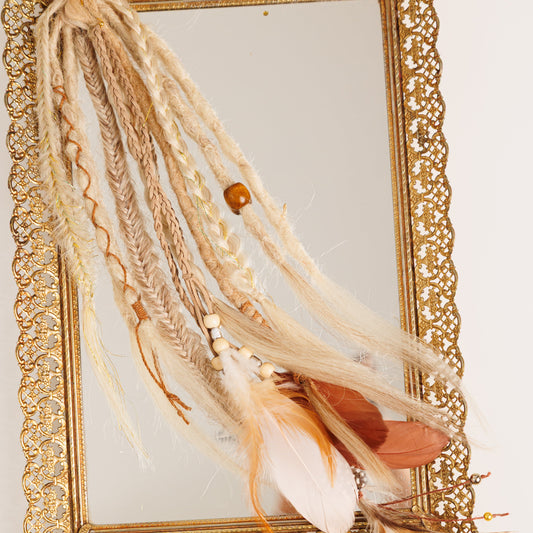 Decorative boho hair with feathers in front of a gold-framed mirror