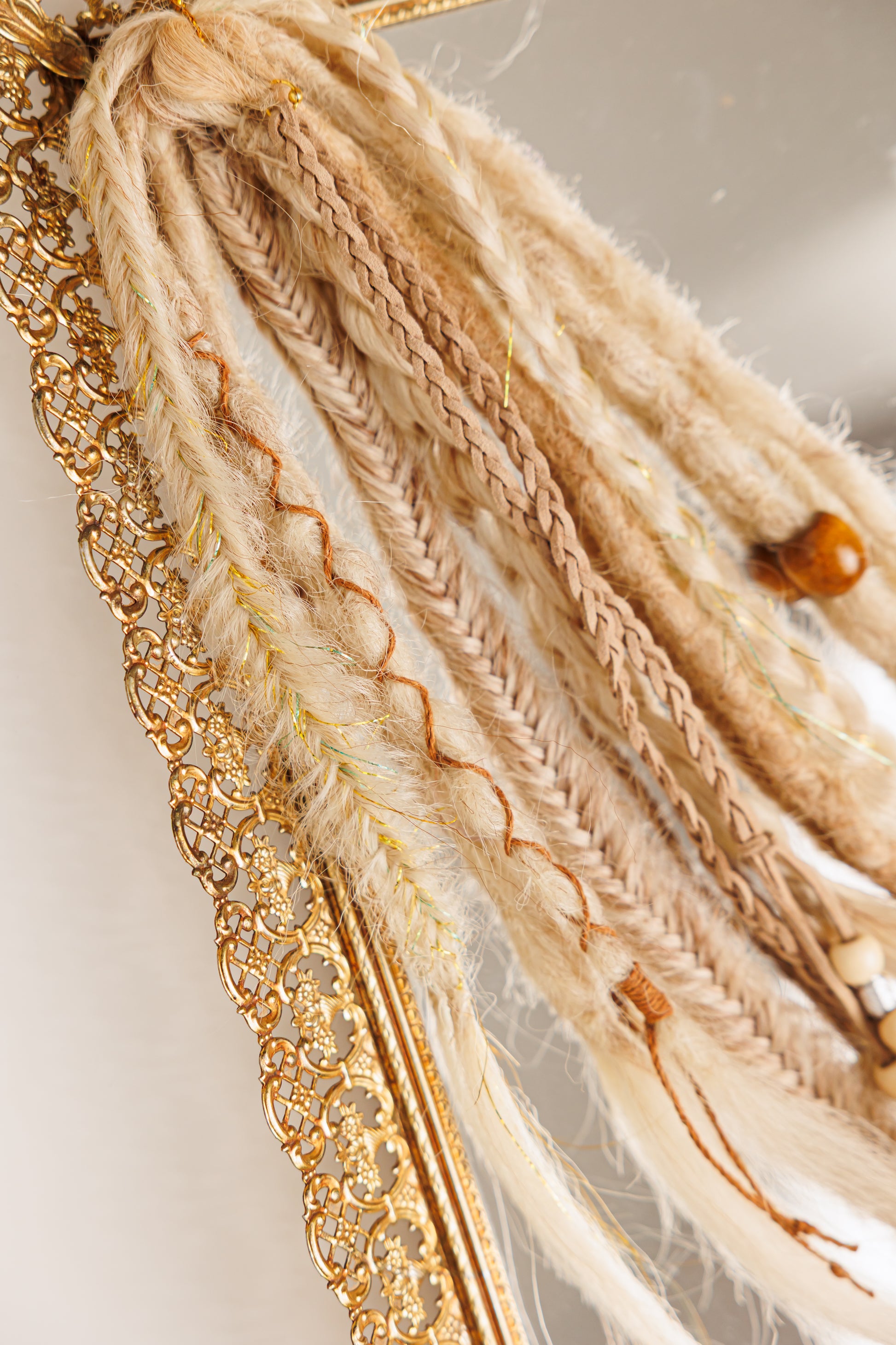 Decorative hair tie with braided design and gold chain on a neutral background