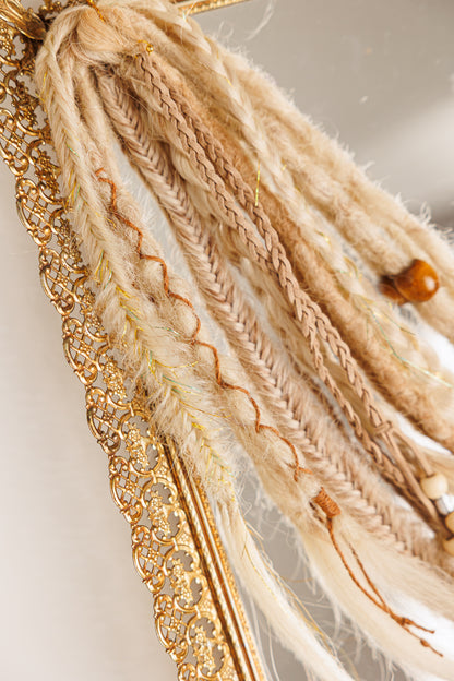 Decorative hair tie with braided design and gold chain on a neutral background