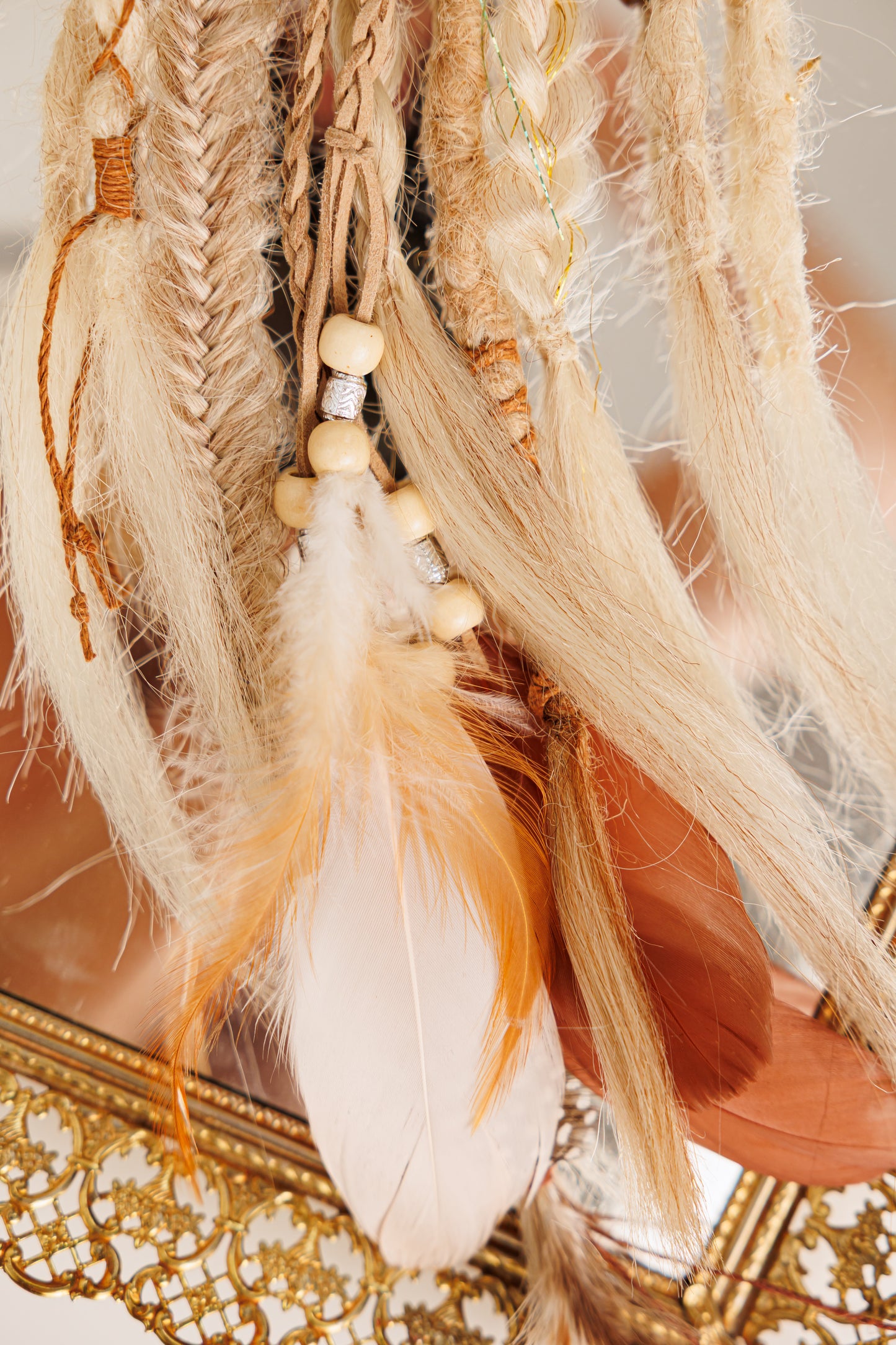 Decorative hair accessory with feathers and beads on a textured surface