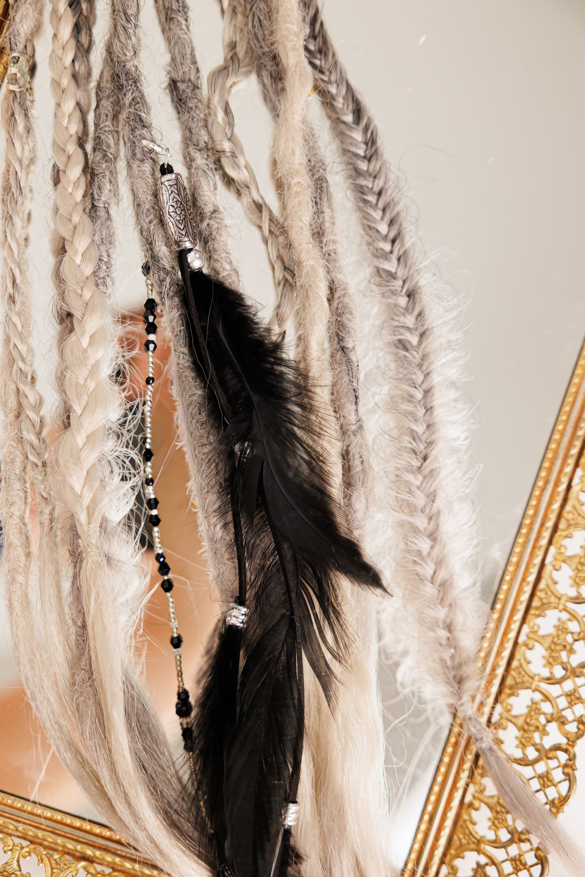 Feather hair extension with beads against a neutral background