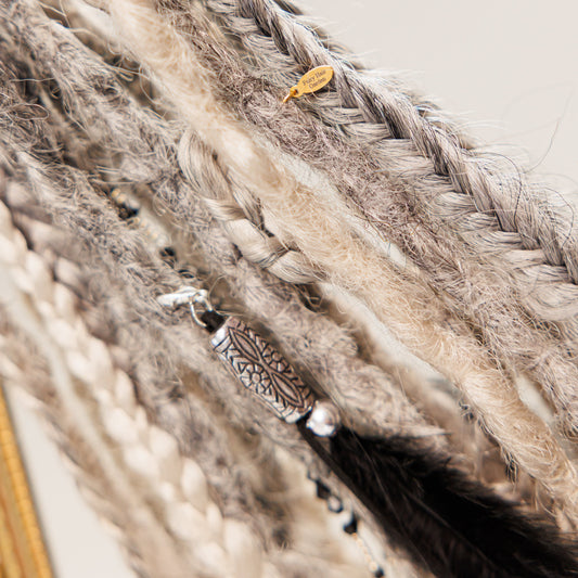Handcrafted boho braided fibers with metallic charm and feather, unique wall decor accent.