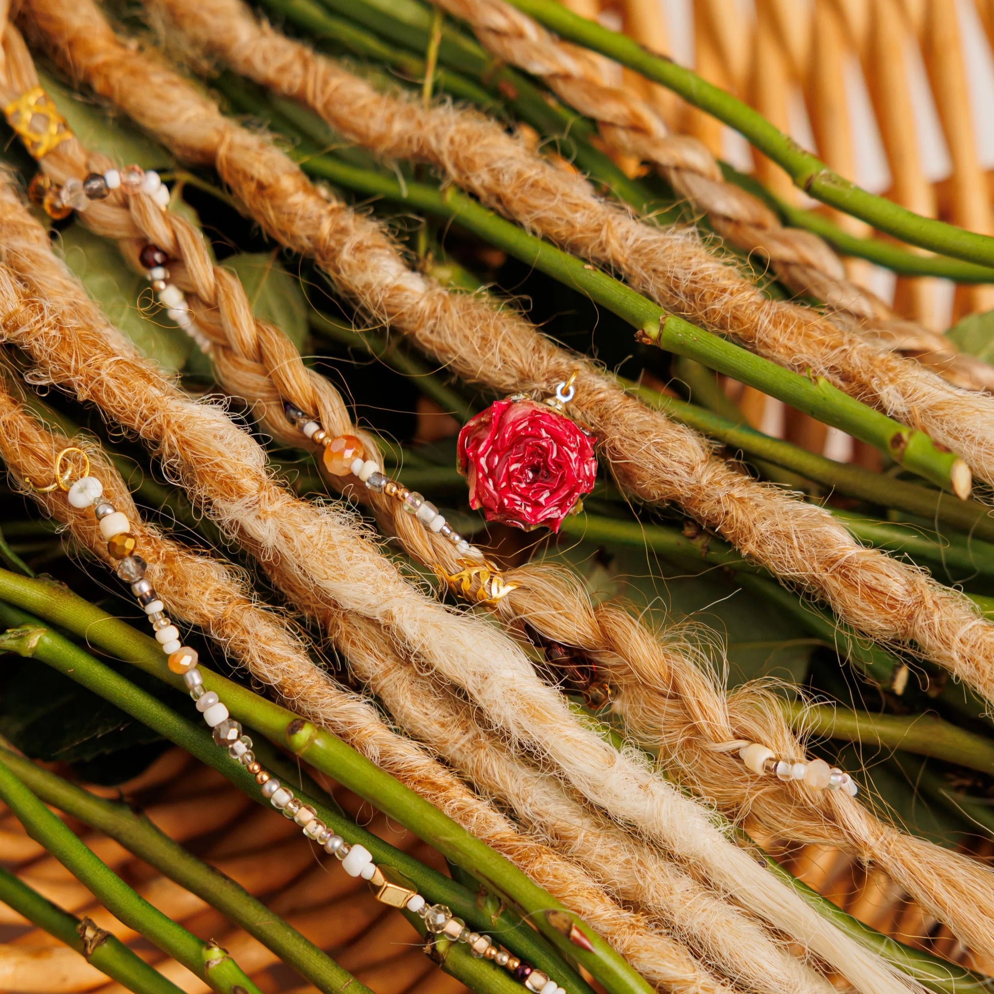 soft blonde dreadlocks and twisty braids nestled in a woven basket with fresh pink roses