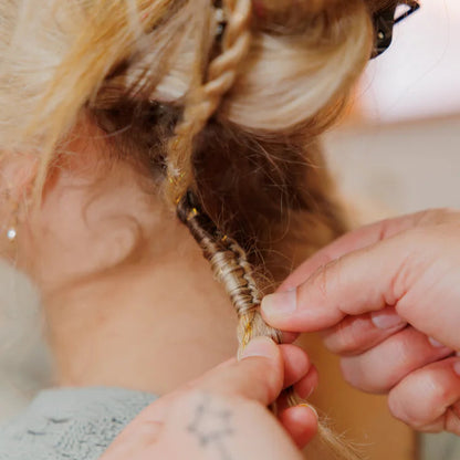 Close-up of hands braiding a person's hair with a blurred background