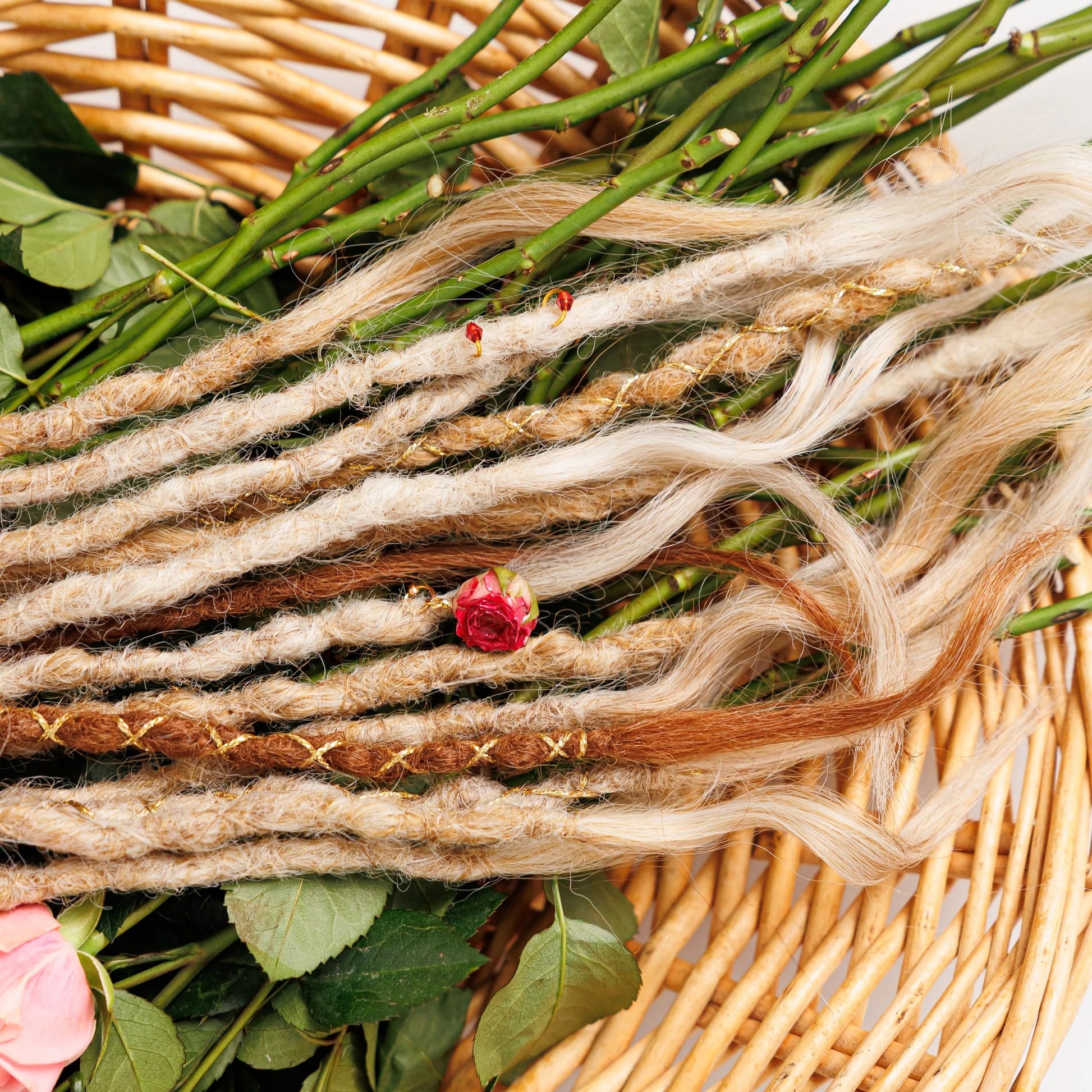 light blonde ombré dread braids with warm red undertones and fairy sparkle laid on linen with rose buds