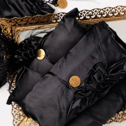 Black satin fabric with gold buttons and tassels on a decorative frame