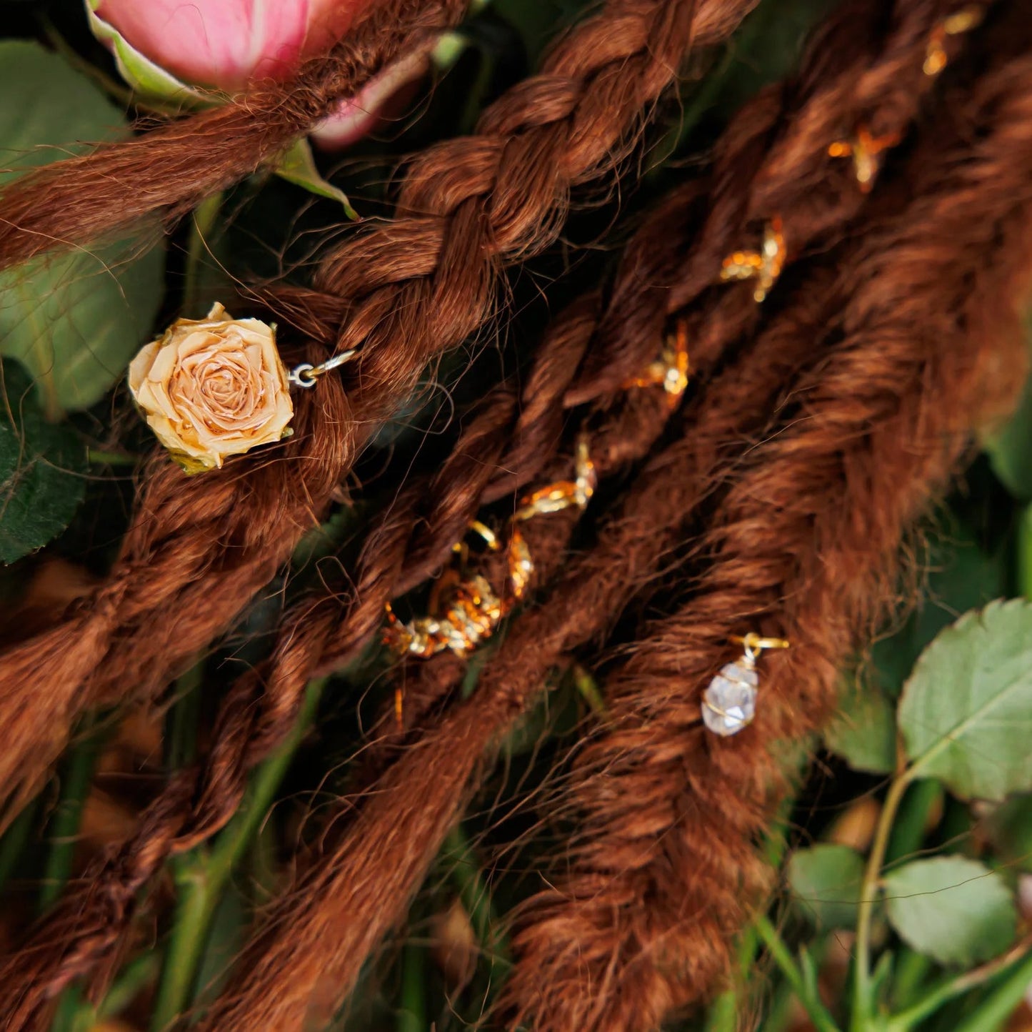 Brown braided and dreadlock hair extensions with decorative elements on a floral background