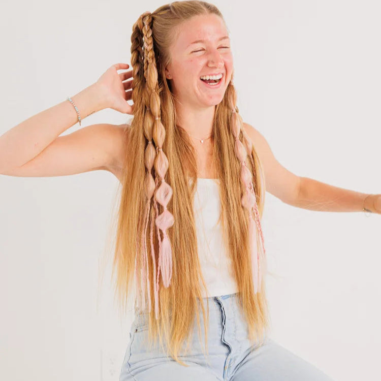 Woman with pink braided hair laughing on a white background