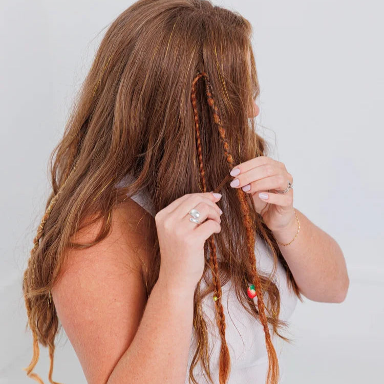 Reddish-brown hair braided with colorful beads, styled in creative boho fashion against light background.