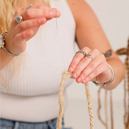 Person holding braided hair extensions with a neutral background