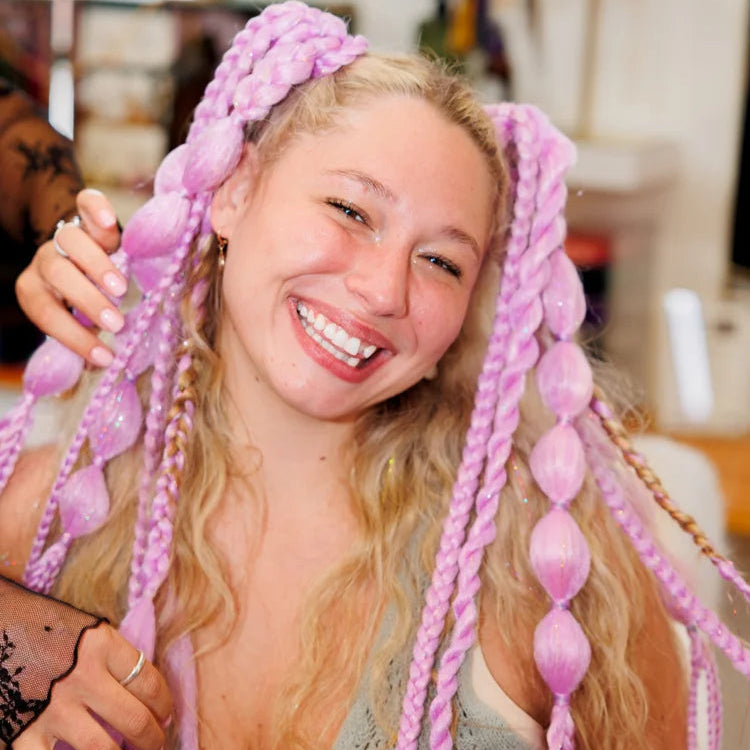 Person with pink braided hair extensions in a casual indoor setting