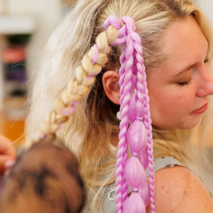 Woman with braided hair, including pink braids, in a salon setting.