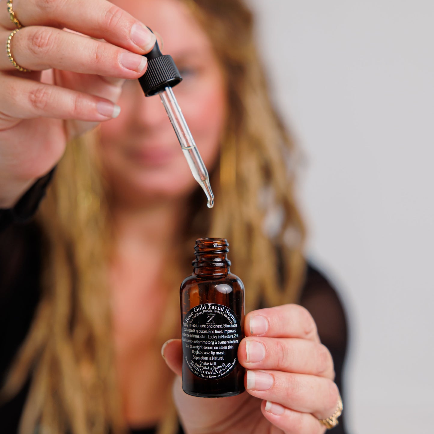 Person holding a dropper over a small brown bottle with a label.