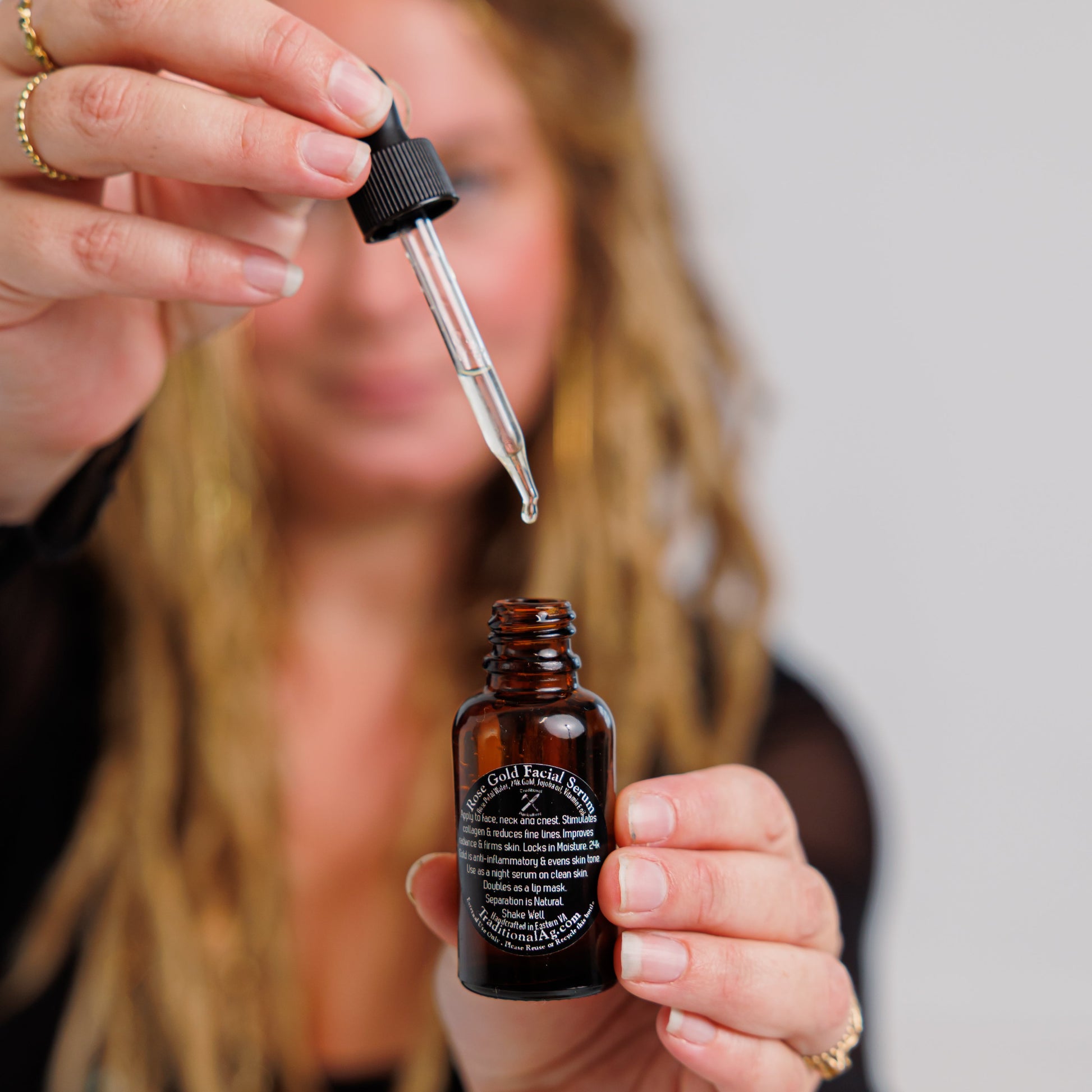 Person holding a dropper over a small brown bottle with a label.