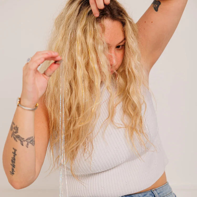Person with long blonde hair trying to war the fairy hair clip ins, standing against a plain background.