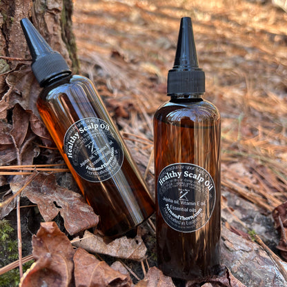Two brown bottles with black nozzles on a leafy ground with a blurred natural background