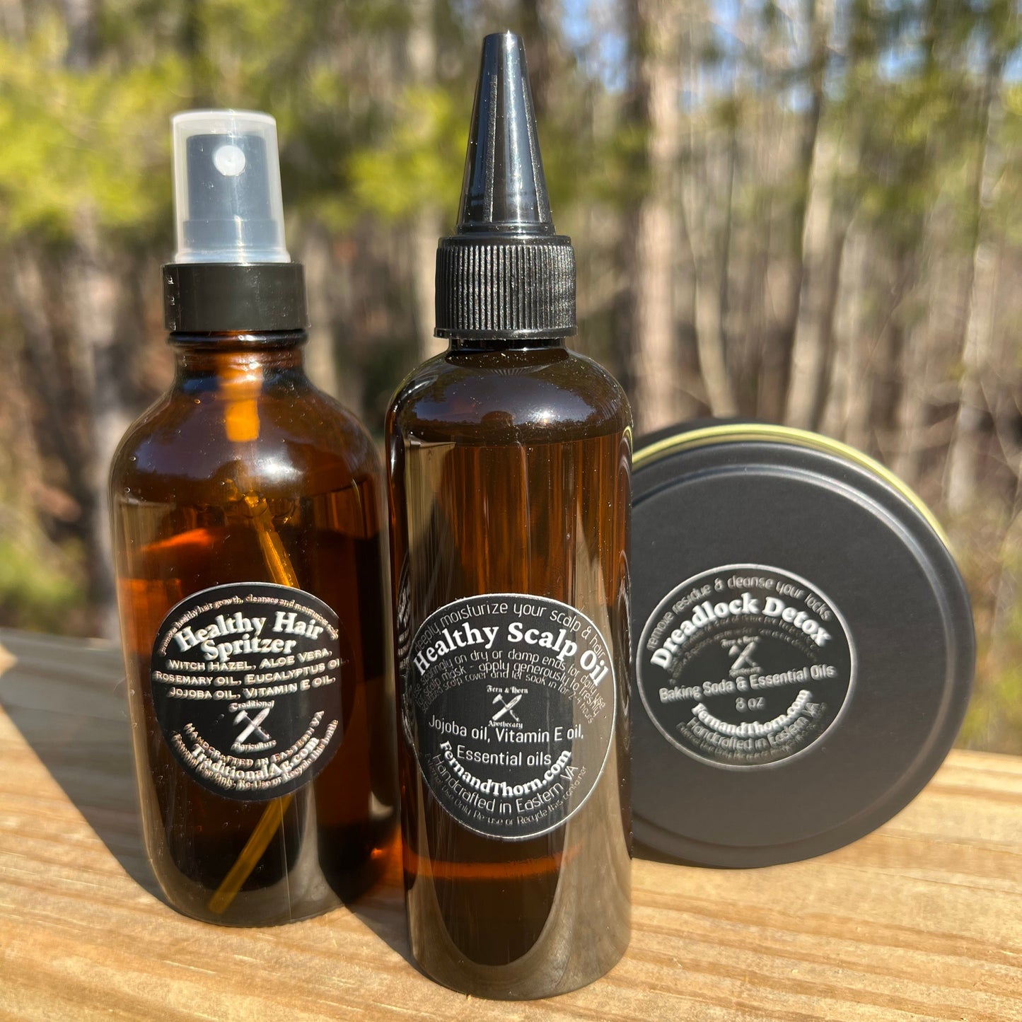 Three bottles of healthy scalp oil products on a wooden surface with a blurred natural background.