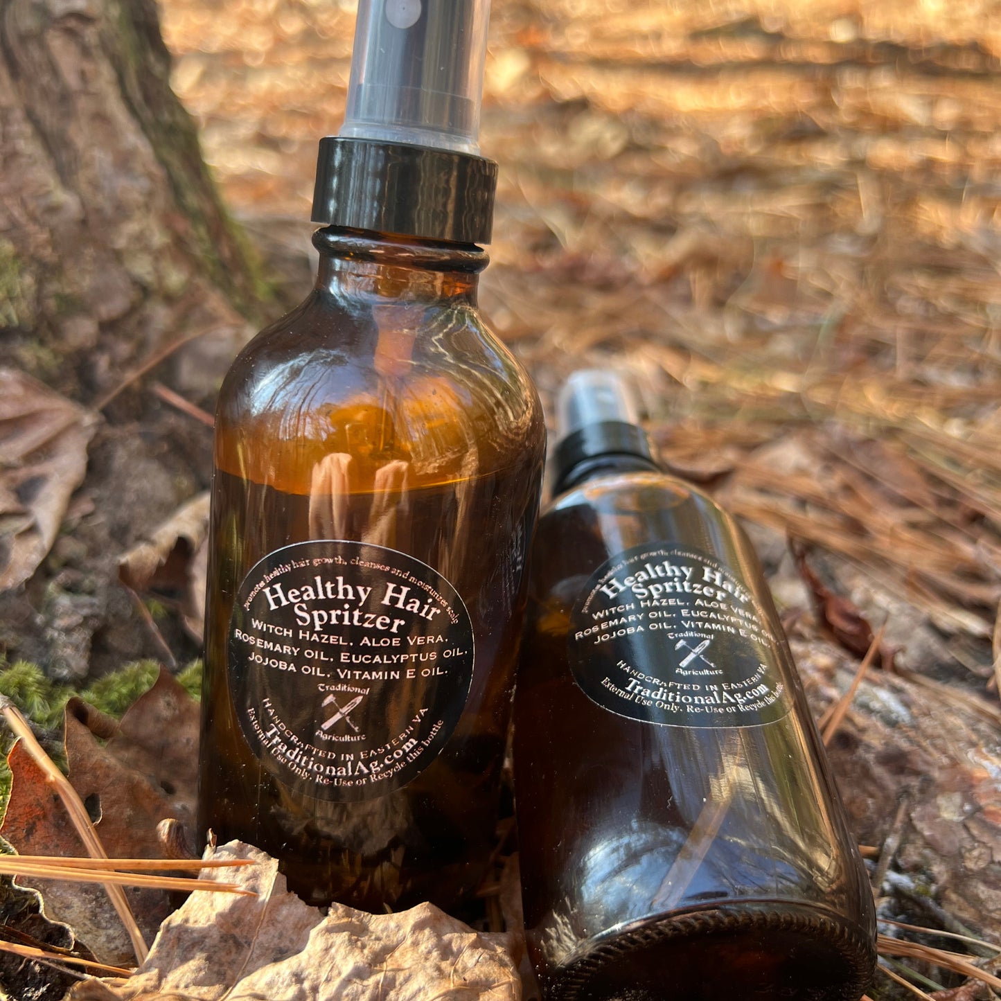 Two bottles of healthy scalp spritzer on a natural background with leaves and branches.