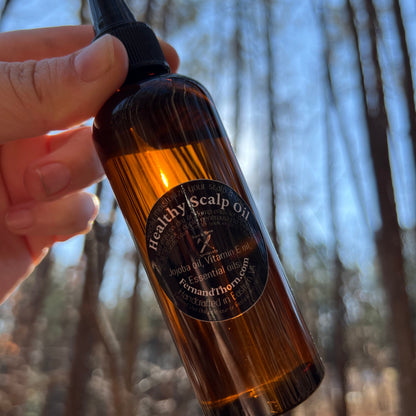 Hand holding a brown bottle with a label against a blurred natural background