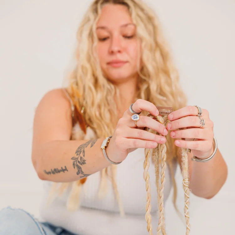 Woman sitting on the floor with braided hair, holding a boho hair extension