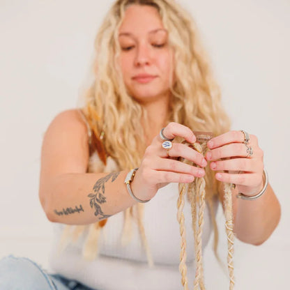 Woman sitting on the floor with braided hair, holding a boho hair extension