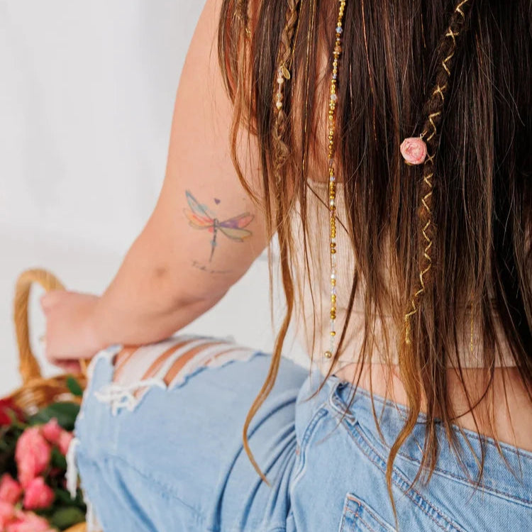 Person with braided hair, sitting next to a basket of flowers.