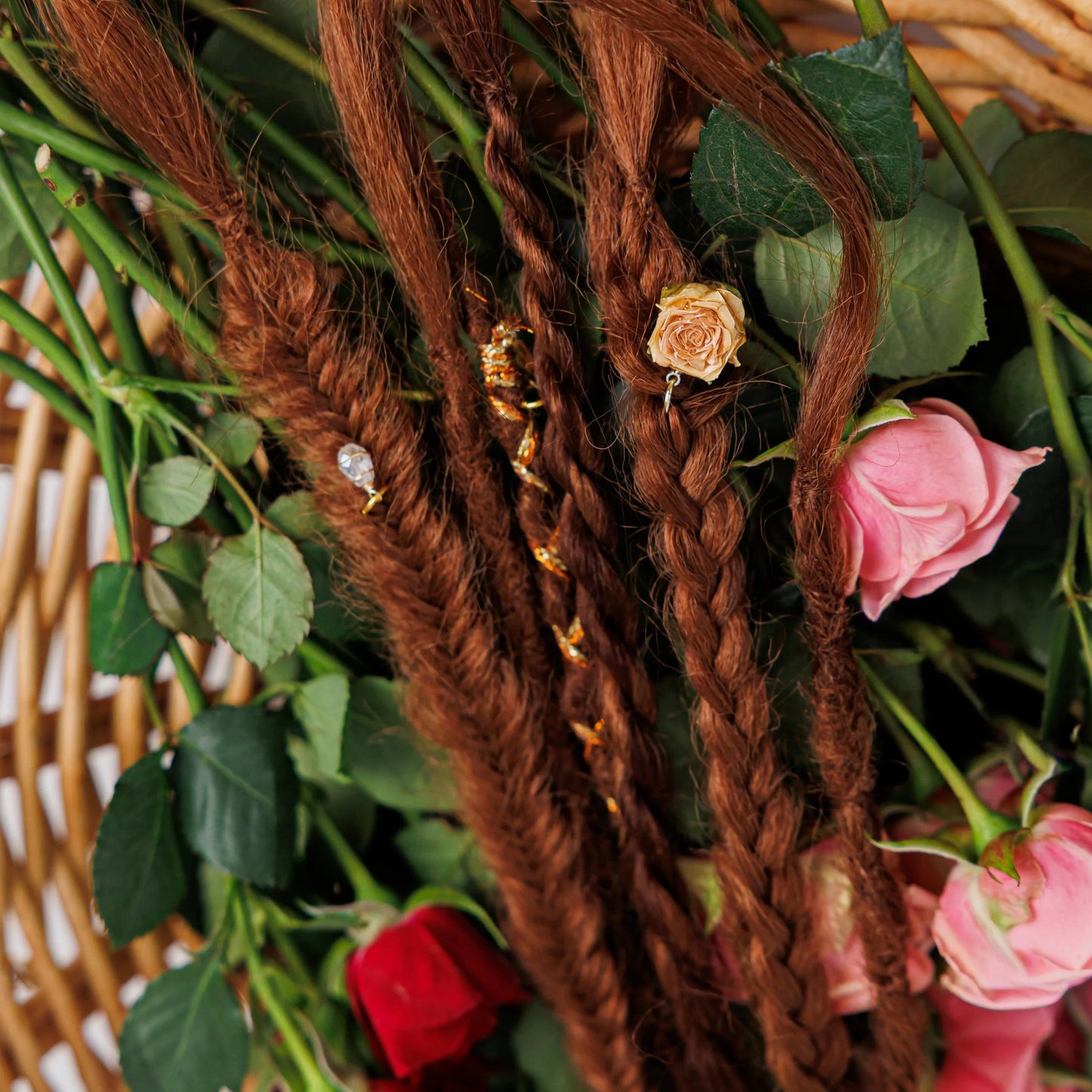 red boho hair extensions with deep copper undertones styled beside scattered rose petals and twine