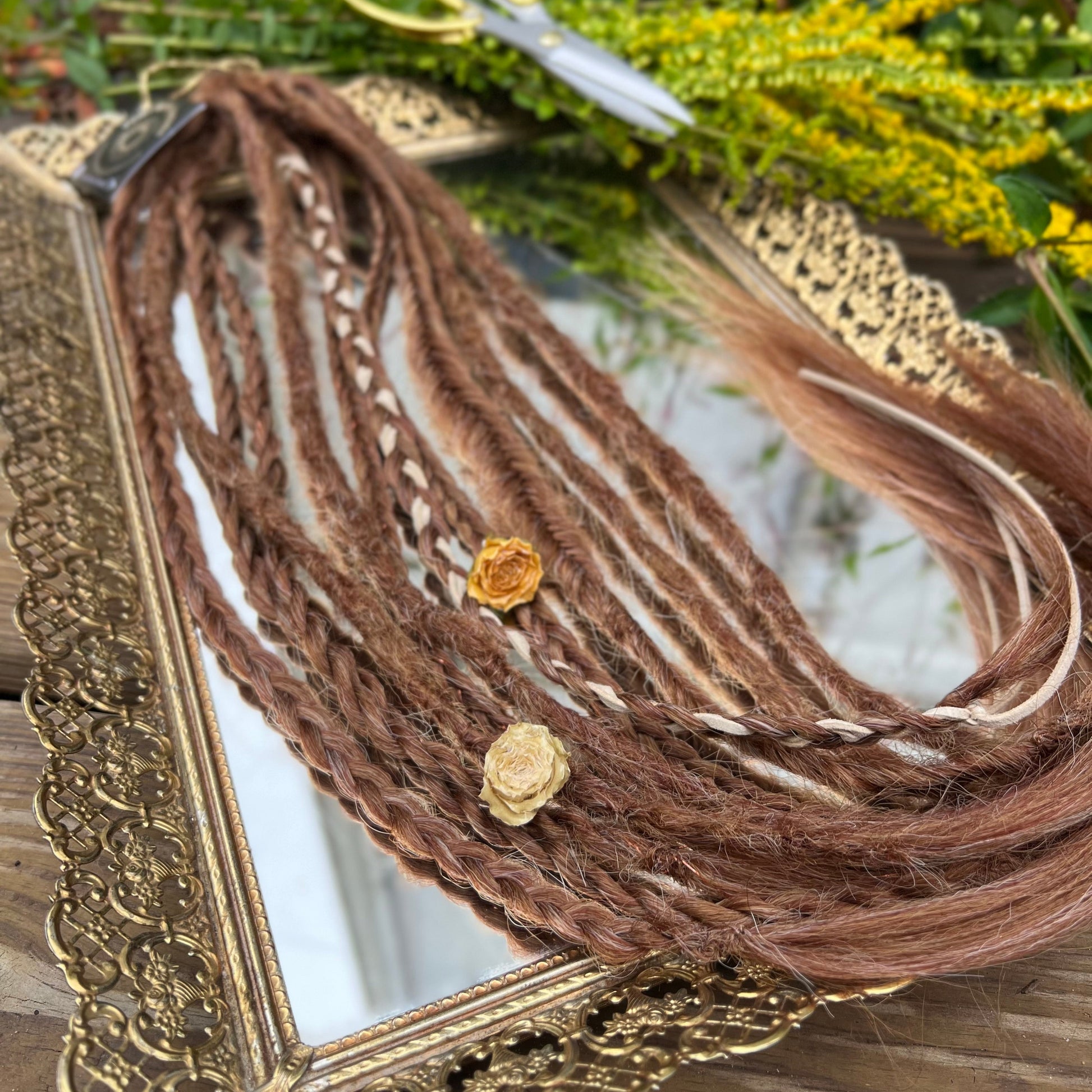 Braided brown hair extensions with a gold frame and scissors in the background