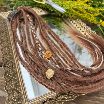 Braided brown hair extensions with a gold frame and scissors in the background