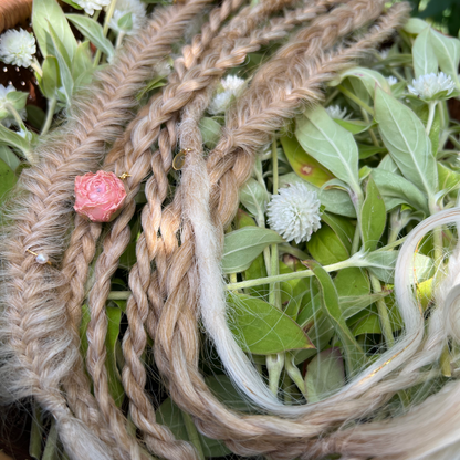 blond braided hair with pink flower and green leaves in a woven basket